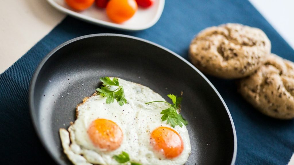 two fried eggs in a frying pan next to a plate of cookies